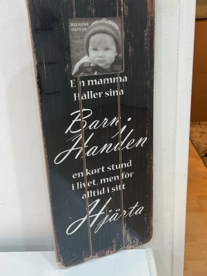 Fotoram  - En svart, träskylt med vit text och plats för ett foto (10x10 cm). Skylten har ett citat om mammor och barn skrivet i snygg kursiv stil. Perfekt som personlig inredningsdetalj eller present. Plasten är fortfarande på