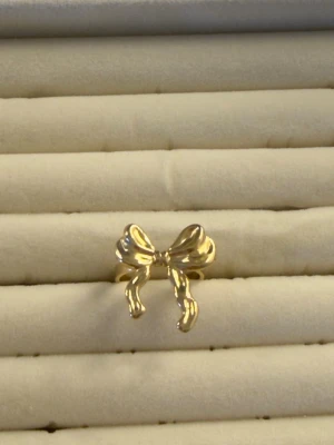 Guldfärgad ring med rosett - Snygg guldfärgad ring i form av en rosett. Ringen har en blank finish och en lekfull design som sticker ut. Perfekt för dig som gillar söta och i trendiga accessoarer. Ingen synlig märkning.