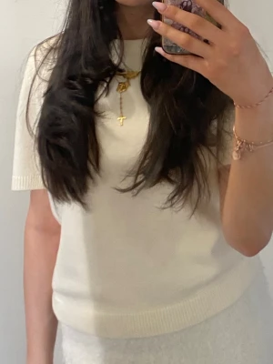 Vit kortärmad stickad topp - Säljer en stilren vit kortärmad stickad topp med rund hals. Toppen har en mjuk och något tjockare kvalitet, perfekt för lager på lager. Passar till både jeans och kjol för en clean look.