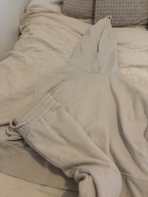 Beige mjukisset med hoodie och byxor från Zara - Säljer ett supermysigt beige mjukisset med hoodie och matchande byxor. Hoodien har luva och breda muddar, byxorna har resår i midjan och dragsko. Perfekt för chill dagar hemma eller när du vill vara extra bekväm. Kom med egna bud och hör av vid intresse
