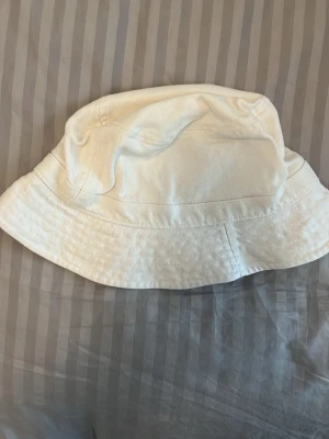 Vit bomulls bucket hat - En vit 100% bomulls bucket hat från monki i storlek l då den är lite oversized på mig i bra kvalitet ovh inga fläckar eller märken.