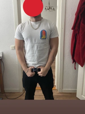 Vit t-shirt från Casablanca - Säljer en vit t-shirt från Casablanca med färgglad grafisk detalj på bröstet. T-shirten har rund hals och korta ärmar, tillverkad i mjuk bomull. Perfekt för dig som gillar stilrena plagg med en twist.