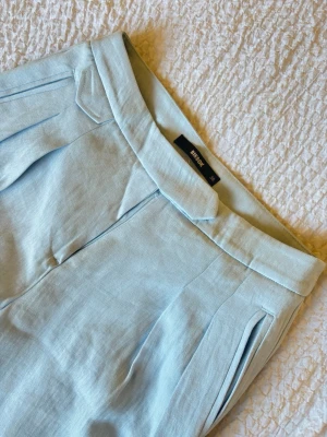 Ljusblå linnebyxor från Bik Bok - Snygga ljusblå linnebyxor från Bik Bok med hög midja och raka ben. Byxorna har diskreta sidofickor och stängs med dragkedja fram. Tillverkade i ett luftigt linnematerial som passar perfekt till varmare dagar. Har aldrig blivit använda, har legat i garderoben och vill bli av med dom. 
