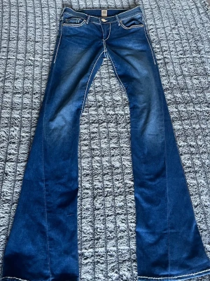 Low waist y2k bootcut jeans  - Säljer ett par blå bootcut jeans med tydliga kontrastsömmar och ikoniska broderade bakfickor. Midjemått är 34cm (68cm) och innerbenslängden är 84.