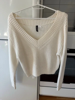 Vit stickad tröja från Divided - Säljer en mysig krämvit stickad tröja från H&m med djup V-ringning och ribbade detaljer. Storlek XS.