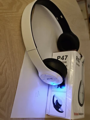 Trådlösa hörlurar P47 vit/svart - Lätta trådlösa hörlurar från P47 i vit och svart plast. On-ear-modell med mjuka öronkuddar och justerbart band. Bluetooth 5.0+EDR för smidig anslutning. Perfekta för musik, gaming eller videos. LED-indikator på sidan. Hörlurar har radio och tar Micro SD kort. Laddas med micro USB kabel.