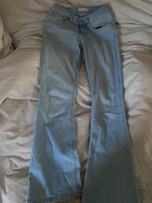 Ljusblå bootcut jeans - Säljer ett par ljusblå jeans med bootcut passform och klassisk femficksdesign. Skulle säga att jeansen har medelhög midja men mer åt de lägre hållet😊säljer då dom inte passar längre, men perfekt i längden på mig som är 160