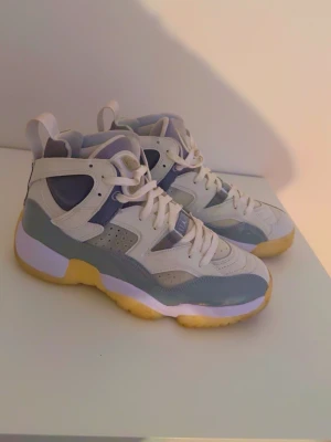 Nike sneakers vita och grå high - Snygga Nike sneakers i high-modell med vit, grå och ljusgul färgkombination. Skorna har perforerade detaljer på sidan, meshpaneler och klassisk snörning. Yttersulan är gul och ger en retrovibe. Perfekta för dig som gillar streetwear och sportig stil.