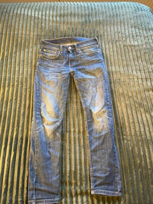 Levi's ljusblå jeans - Säljer ett par klassiska ljusblå jeans från Levi's med raka ben och fem fickor. Jeansen har den ikoniska röda Levi's-lappen bak och är gjorda i slitstark denim. Perfekta till en avslappnad look och passar till det mesta. W28 L30