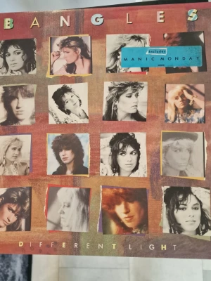 Bangles Different Light vinyl - Lp med snyggt vinylomslag till albumet 'Different Light' av Bangles. Omslaget har ett rutmönster med färgglada och svartvita foton på bandmedlemmarna samt texten 'Includes Manic Monday'. Perfekt för dig som gillar 80-talsmusik och samlar på klassiska albumomslag. Inga repor.