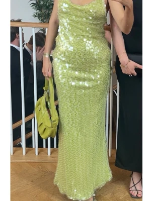 Lång limegrön paljettklänning - Säljer en lång, figurnära klänning i limegrönt med glittriga paljetter över hela plagget. Klänningen har ärmlös design och rundad urringning. Perfekt för dig som vill sticka ut på festen med en unik och glittrig look✨Jag är 170cm för referens! Köpt här på Plick som ny tidigare för 2000kr, endast använd en gång!  