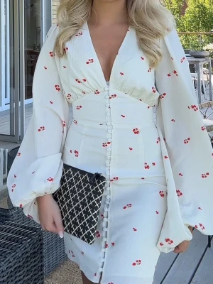 Vit kort klänning med blommigt mönster - Jättefin inprincip oanvänd kort adoore klänning.      Insett att knappen längst ner är borta, skriv för bild. Inget man enligt mig tänkeer på eller märker!       Intressekoll