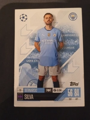 Topps fotbollskort Manchester City - Samlarfotbollskort från Topps med Manchester City-tema. Kortet har blå och vita färger, visar en spelare i matchställ och innehåller statistik samt klubbens logga. Perfekt för samlare eller fotbollsintresserade.