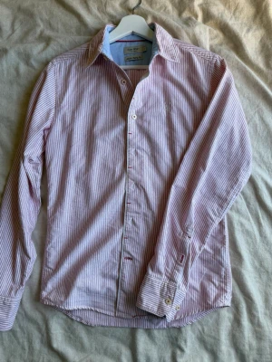 Randig skjorta från East West - Snygg skjorta från East West med rosa och vita ränder. Sitter väldigt bra i storleken och är en perfekt skjorta nu till sommaren.