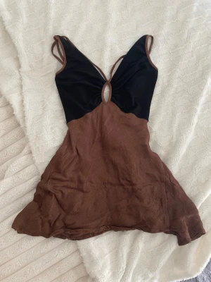 Brun och svart omlottklänning - Säljer en jätte fin brun och svart klänning med öppen rygg från Bec & Bridge. Köpt på sellpy för 450kr och den är i jätte bra skick men passade tyvärr inte mig. Sitter tajt och smickrande i midjan. Pris kan diskuteras! 