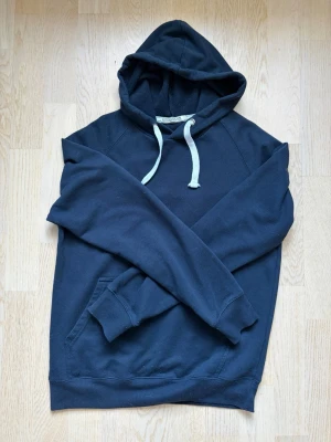 Mörkblå hoodie från Enos Jeans - Mörkblå hoodie från Enos Jeans med klassisk huva och vita dragsnören. Tröjan har ribbade muddar vid ärmarna och nederkant samt en magficka framtill. Perfekt för en avslappnad och stilren look. Denna köptes på miinto för nypris 1000+, minns inte riktigt! Denna säljs för den helt enkelt blivit för liten! Kan gå ner lite i pris om du följer!