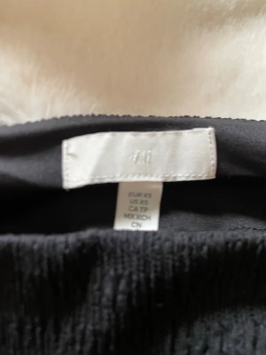 Svart offshoulder topp från H&M - Trendig svart offshoulder topp från H&M i smockat tyg. Toppen har lång ärm och en tight passform som framhäver axlarna. Perfekt för dig som gillar en stilren och modern look. Ny utan prislapp