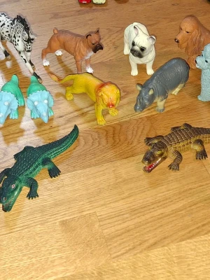 Samling plastdjur och leksaksbilar - Säljer en blandad samling plastdjur och leksaksbilar. Djuren inkluderar lejon, hundar, krokodiler, noshörning, dinosaurier och fler, i olika färger som grön, gul, brun och blå. Perfekt för lek eller samling. Bilarna är i olika modeller och färger.