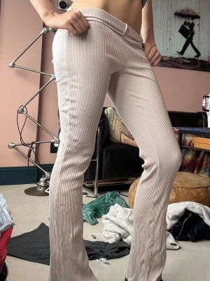 Beige ribbade utsvängda byxor - Säljer ett par beige ribbade byxor med utsvängda ben från H&M. Byxorna är mjuka och strechiga. Buda gärna priser!