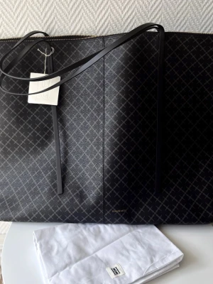 Ny By Malene Birger ”Leesa” Weekendbag - Helt ny med tags kvar enligt bilder!  Lessa är en perfekt rymlig weekendväska från Malene Birger, som du också med fördel kan använda som en shopper. Praktisk innerficka som stängs med dragkedja samt dustbag medföljer.  Storlek 42x66x20cm  Färg: Black/grey  Nypris 4200kr
