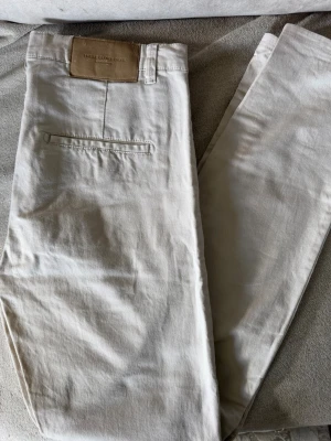 Beige chinos från These Glory Days - Snygga beige chinos med klassisk rak passform. Byxorna har diskreta bakfickor och är tillverkade i mjukt bomullstyg. 