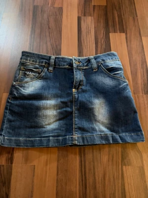 Blå jeanskjol  - det står storlek 29, men jag skulle nog säga att den motsvarar storlek S ungefär! Snygg blå jeanskjol från med klassisk femficksdesign, bälteshällor och knappstängning framtill. Kjolen har en kort passform och slitna detaljer för en cool look!💕