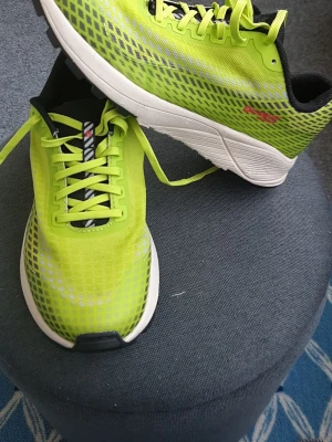 Neongröna Inov-8 sneakers - Snygga neongröna sneakers från Inov-8 med svart och vitt mönster på plösen och svarta detaljer. Ovandelen är i mesh för bra ventilation och sulan är vit med svart yttersula. Perfekta för dig som vill sticka ut och ha riktigt lätta skor.