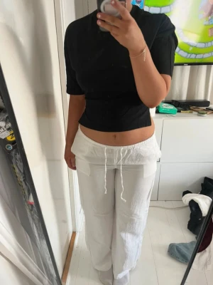 Vita linnebyxor - Säljer ett par vita linnebyxor med avslappnad passform och dragsko i midjan. Byxorna har raka ben och stora fickor framtill, perfekta för en chill och stilren look. Materialet är luftigt linne som passar bra till varma dagar.