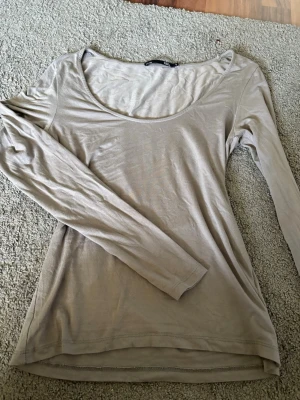 Grå långärmad topp från lager 157 - En enkel och stilren grå långärmad topp från lager 157 med rund halsringning. Toppen är i ett mjukt och tunt material som känns skönt mot huden. Perfekt att matcha med jeans eller kjol för en clean look.
