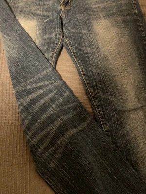 Blå skinny jeans med slitningar - Säljer ett par blå skinny jeans med snygga slitningar och tvättade detaljer. Jeansen är i stretchigt material med 98% bomull och 2% spandex för en bekväm passform. Storlek 30/32. Perfekta för en trendig och avslappnad look.