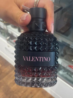 Parfym - Snygg parfymflaska från Valentino med svart lock och nitar i glaset. Flaskan har en cool, mörk toning från svart till transparent och loggan valentino i rosa på svart etikett. Perfekt för dig som gillar exklusiva och trendiga dofter. Bara två spray använda. 
