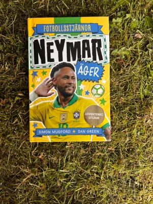 Neymar äger - Fotbollsstjärnor - En färgstark bok om fotbollsstjärnan Neymar, skriven av Simon Mugford och Dan Green. Omslaget är gult med gröna och blå detaljer, och boken är inbunden. Perfekt för dig som gillar fotboll och vill veta mer om Neymars resa till toppen.