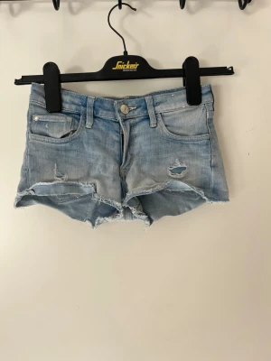 Ljusblå jeansshorts med slitningar - Snygga ljusblå jeansshorts med råa kanter och slitna detaljer framtill. Finns ingen lapp men skulle säga storlek XXS