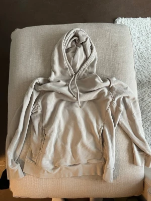 Beige hoodie from H&M - En beige hoodie från H&M i storlek M med luva och snören. Tröjan har en ficka framtill.