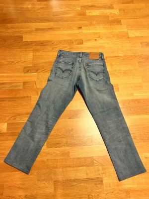 Blå raka jeans från Levi's 29/30 - Säljer ett par klassiska blå jeans från Levi's med raka ben och femficksdesign. Jeansen har en snygg tvättad look och ikoniska bakfickor med Levi's-signaturen. Perfekt för dig som gillar tidlös stil och komfort. Storlek 29/30. 29/32 i grunden men de e uppsydda och sitter som 29/30