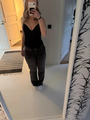Svarta raka jeans med låg midja - Säljer ett par svarta raka jeans med låg midja och klassisk femficksdesign. Jeansen har en avslappnad passform och är perfekta för en casual look. Materialet känns som bomull med lite stretch för extra komfort. Nypris 1000