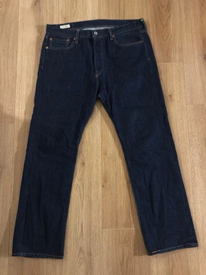 Jeans Levi's jeans  - Säljer ett par klassiska mörkblå jeans från Levi's med raka ben och fem fickor. Jeansen har snygga kontrastsömmar och en ikonisk läderpatch bak. Perfekta för dig som gillar tidlös denimstil.
