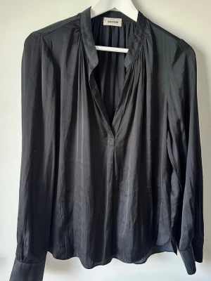 Svart blus från Zadig & Voltaire - Stilren svart blus från Zadig&Volyaire med djup v-ringning och lätt rynkade detaljer vid halsen. Använd ca 3 gånger. Storlek S 🩷
