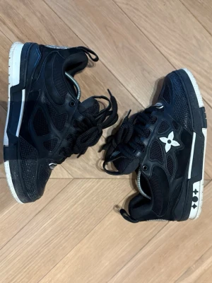 LV Skate sneakers - Säljer dessa riktigt feta nygga skate sneakers från Louis Vuitton med LV-logga på tungan och ikoniska blommor på sidan och hälen. Skorna har kraftiga svarta snören, meshpaneler och detaljer i läder. Yttersulan är vit med svarta inslag. Perfekt för dig som vill ha en exklusiv look. De är i storlek 41. Skorna är i bra skick och sitter skönt. Pris kan diskuteras