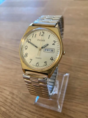 1994 Seiko Pulsar DayDate Gold Plated 35mm Herrur - Vintage Pulsar kvartsklocka med dag- och datumvisning. Klockan har ett Guldpläterad boett och ett flex-stålarmband i guldton. Urtavlan är ljus med arabiska siffror och visare.  Även självlysande, vattentät, japanskt urverk osv. Fint skick enligt bilder. Har fungerande batteri! Modellnummer 4160541/V533-8A70.  Begagnat värde: < 1500 SEK Mitt pris: 589 SEK  Skickas alltid snabbt och spårbart. Skriv vid frågor och se gärna mina andra annonser!   GRATIS: För återkommande kunder erbjuder jag personli