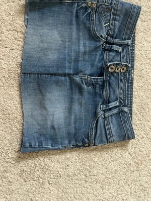 Kort jeanskjol - Säljer en blå jeanskjol i kort modell med snygga fickor bak, varav en har dragkedjedetalj. Kjolen har tre knappar framtill och klassiska jeanssömmar. Perfekt för dig som gillar en avslappnad och cool stil. Ps jag har även sytt den lite kortare ❤️