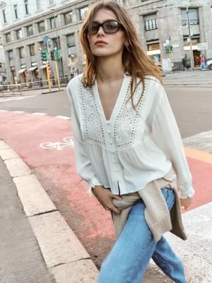 Vit blus med broderi och knappar - Säljer en luftig vit blus från Zara med v-ringning, dekorativa knappar framtill och broderade detaljer på bröstet. Blusen har långa ärmar och är gjord i ett tunt, strukturerat tyg som ger en avslappnad men ändå chic look. Perfekt till vår och sommar!