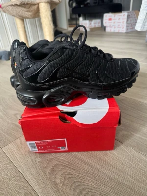 Nike Air Max Plus  - Nike Air Max Plus sneakers i helsvart färg med mesh och syntetmaterial. Skorna har en chunky sula med Air Max-dämpning och ikoniska vågformade detaljer på ovandelen. Perfekt för dig som gillar en sportig och modern look.