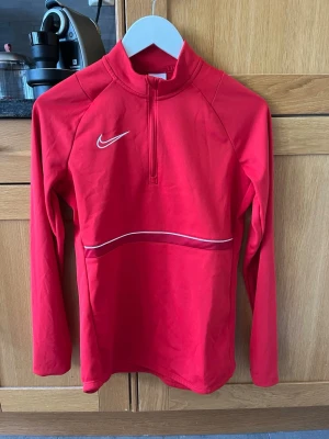 Nike tröja - Säljer en Nike sporttröja i färgen röd. Nike loggan sitter på högra bröstet 