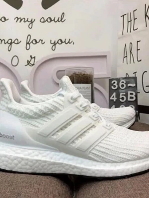 Vita Adidas Ultraboost sneakers - Fräscha helvita Adidas Ultraboost sneakers med stickad ovandel och klassiska tre ränder på sidan. Skorna har en chunky Boost-sula för maxad komfort och sportig vibe. Perfekta för dig som gillar stilrena och moderna sneakers.