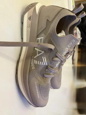 Emporio Armani, Armani, sneakers i toppenbra skick.  - Emporio Armani, EA7, sneakers i mycket bra skick/perfekt skick. Endast använda/prövade ett par tillfällen. Jättefin färg: Beige / Champange. Ovandelen är stickad/sockmodell. Väldigt sköna.  Storlek 41 1/3.    Skriv gärna om du har frågor eller önskar fler bilder:)   Jag skickar snabbt, senast nästa dag.   Med vänliga hälsningar  Mimmi