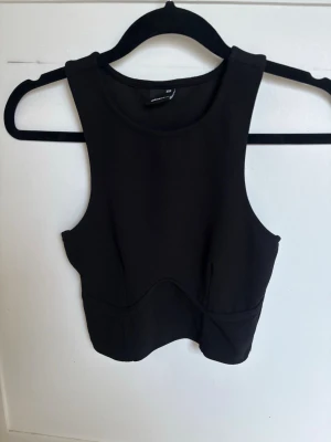 Svart croppad linnetopp från Gina Tricot - Snygg svart croppad linnetopp från Gina Tricot med rund halsringning och breda axelband. Toppen har en figurnära passform och är perfekt att styla med höga jeans eller kjol. Enkel och stilren design som passar till många looks. Storlek XXS men den är stretchig så skulle säga att den även passar en XS 🩷