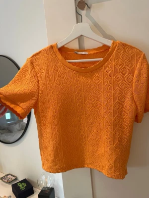 Orange stickad topp från Zara - Snygg orange stickad topp med korta ärmar och vågiga kanter.storlek L men sitter mer som en M