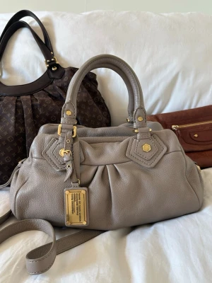 Beige Q Classic Baby Groove bag! - Så fin beige handväska i äkta läder från Marc by Marc Jacobs. Den ikoniska modellen Q Classic Baby Groove! En populär och eftertraktad vintagemodell med gulddetaljer och dubbla handtag. Långa bandet medföljer. Så snygg vintageväska i toppskick, inga skavanker. Ren invändigt och fina gulddetaljer. Svår att få tag på i detta skick. Skriv privat för fler bilder 🤍  Mått: Lilla modellen. 34x18x12 cm (undersida)  Kan hämtas hemma hos mig i Nacka eller skickas 🤍 