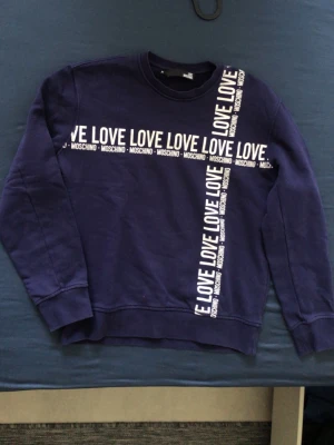 Moschino + HUGO - Mörkblå sweatshirt från Love Moschino, storlek M. Beige HUGO-hoodie ingår, mycket fint skick, oanvänd, storlek M.